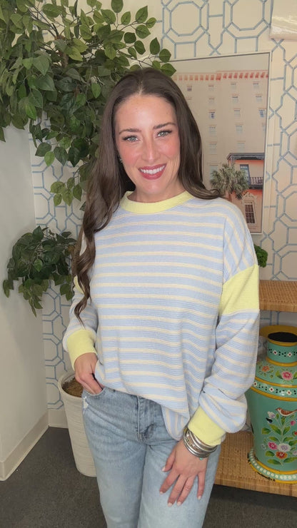 Woman wearing a blue and yellow striped sweater in a room with decorative elements.