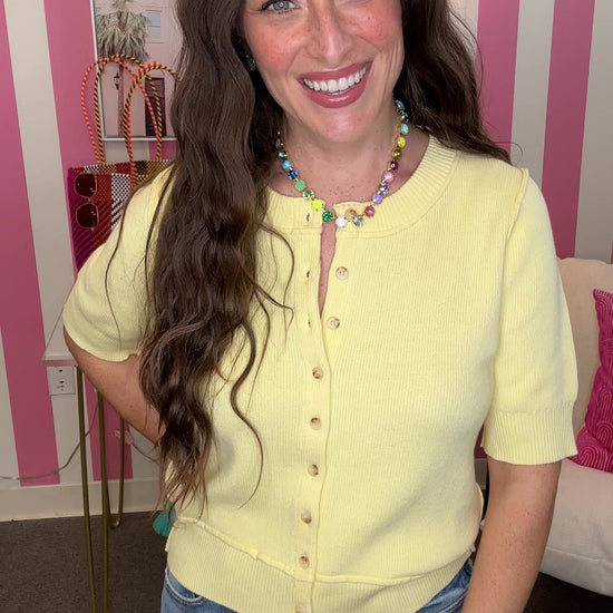Woman wearing a yellow top and blue jeans in a room with pink and white striped walls