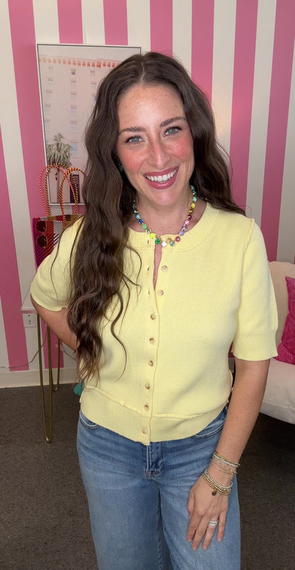 Woman wearing a yellow top and blue jeans in a room with pink and white striped walls