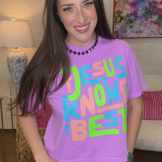 Woman wearing a purple t-shirt with colorful text in a living room setting