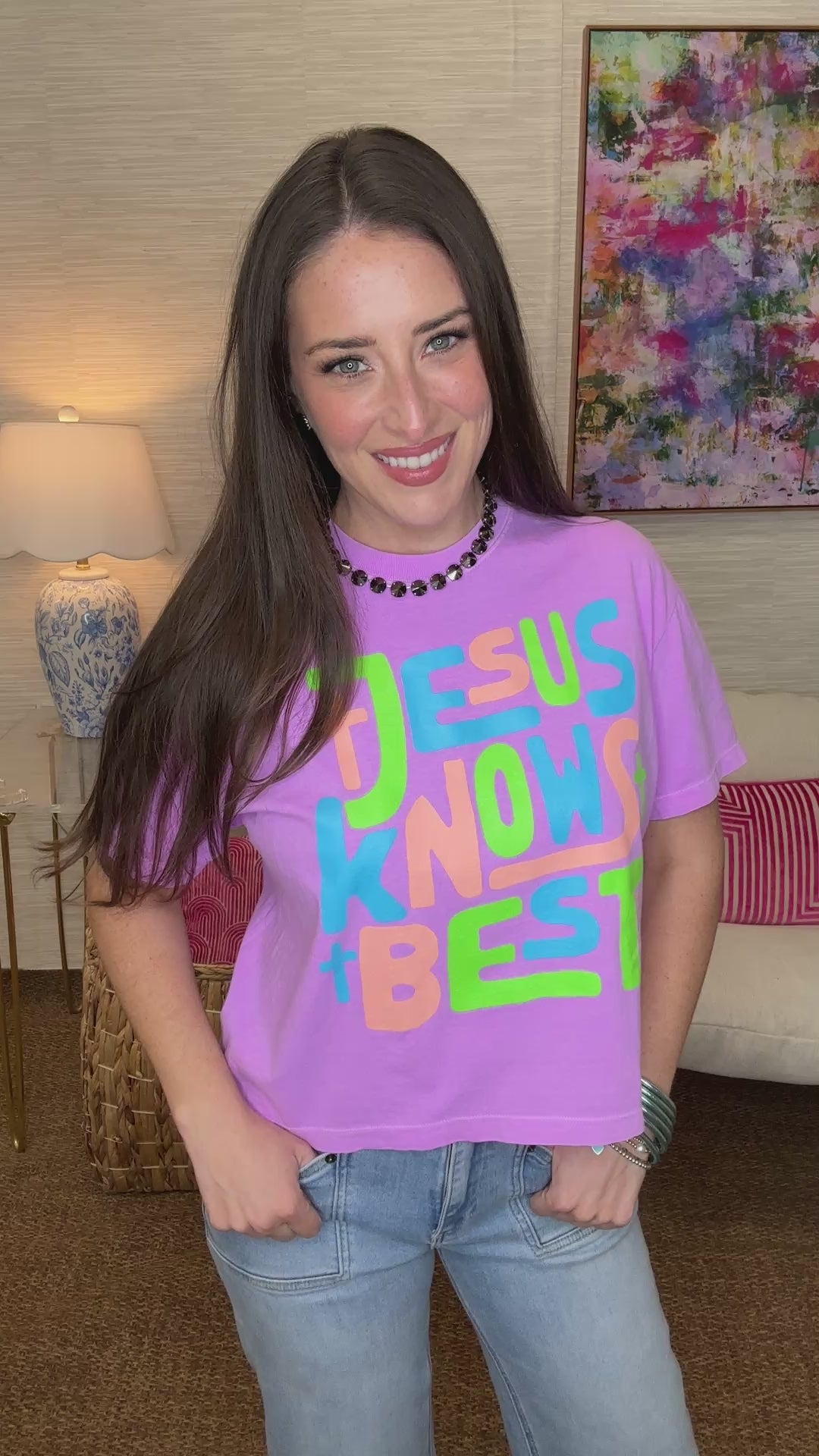 Woman wearing a purple t-shirt with colorful text in a living room setting