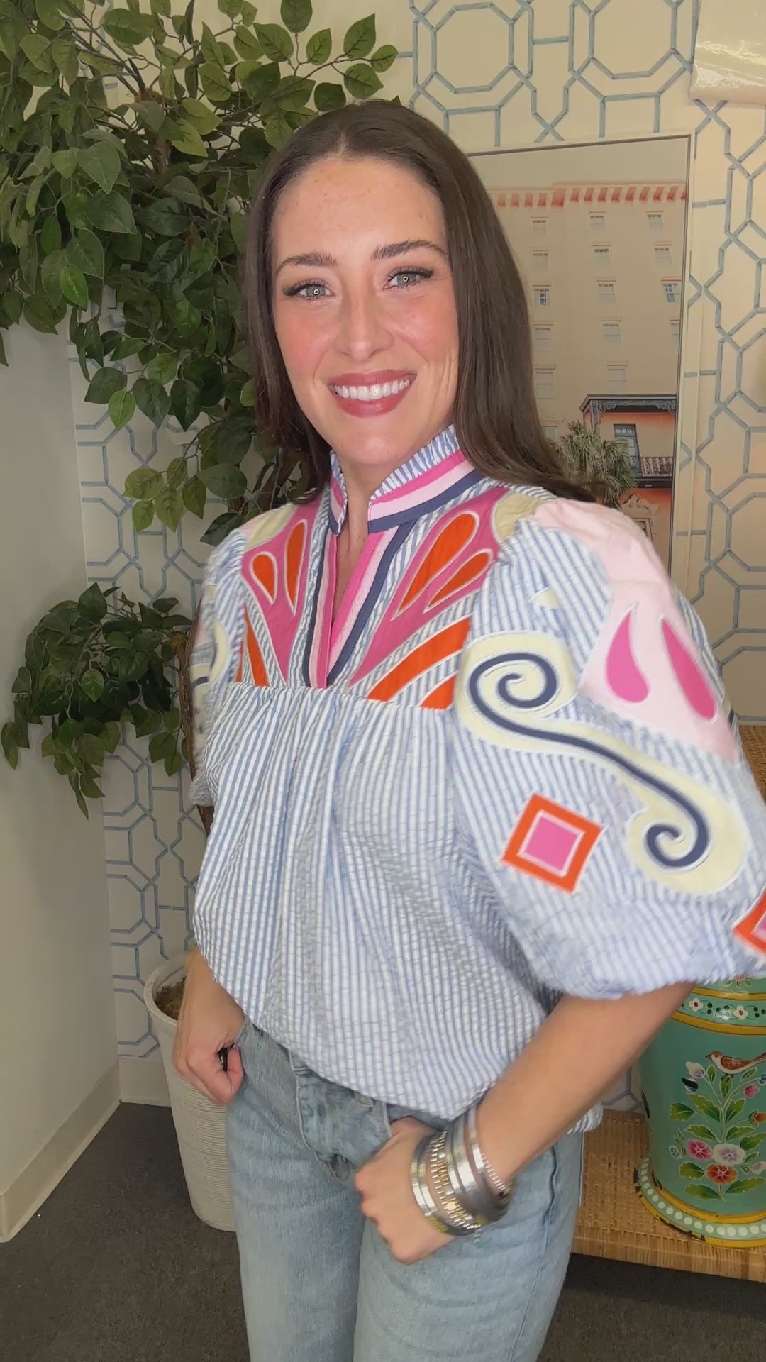 Woman wearing a colorful blouse with puffed sleeves in an indoor setting.